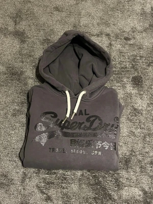 Mörkgrå Superdry hoodie - Säljer en snygg mörkgrå hoodie från Superdry - Storlek S - skick som nytt - pris 599