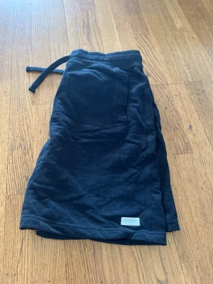 Svarta mjukisshorts från Colorful Standard - Svarta mjukisshorts från Colorful Standard med dragsko i midjan och fickor på sidorna samt en bakficka. Tillverkade i mjukt bomullsmaterial som känns skönt mot huden. Perfekta för chill dagar eller träning.