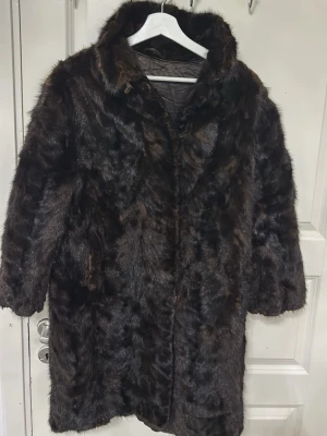 Äkta minkpäls – klassisk mörkbrun kappa – fint skick - Säljer en elegant och tidlös minkpäls från PUB Stockholm. Klassisk modell i mörkbrun nyans med fin glans och tät päls. Kappan är i fint skick med mjuk och välbevarad päls. Fodret är helt. Perfekt för dig som uppskattar vintage, kvalitet och klassiskt hantverk. • Äkta mink • Mörkbrun / nästan svart ton • Knäppning framtill • Helfodrad • Klassisk rak modell Passar ca storlek M–L (beroende på hur man vill att den ska sitta). Kan skickas eller hämtas. 