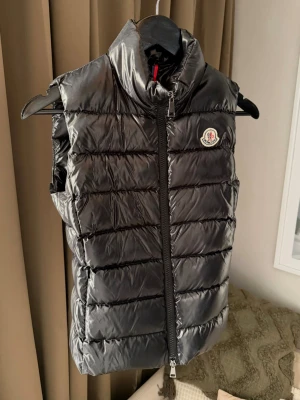 Svart dunväst från Moncler - Snygg svart dunväst från Moncler. Västen har ett quiltat mönster och Moncler-logga på bröstet. Perfekt att slänga över en hoodie eller tröja🤗Nypris 9500🌟