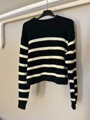 Svartvit randig stickad tröja - Säljer en svart stickad tröja från HM, väldigt varm och skön. Är i XS men passar som en S med.