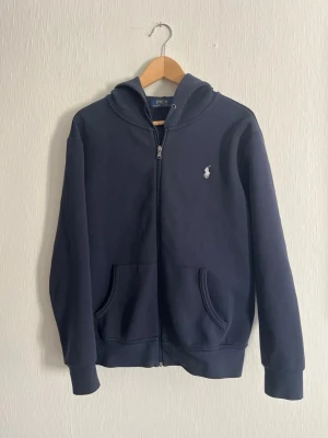 Mörkblå hoodie från Polo Ralph Lauren - Snygg mörkblå hoodie från Polo Ralph Lauren, knappt använd inga defekter. Skriv gärna vid mer frågor🙌🏻