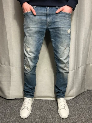 Blåa Replay anbass jeans  - Säljer ett par blåa Replay anbass jeans med slitningar. Storleken är W31 L32. Modellen på bilden är 183 cm o väger ca 70 kg. Skev vid minsta fundering.
