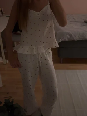 Vit pyjamas med volang och hjärtmönster  - Söt vit pyjamas med små färgglada hjärtan, volangkant nedtill på linnet. Pyjamasen är från Gina tricot, säljer då byxorna inte passar mig längre! 💕