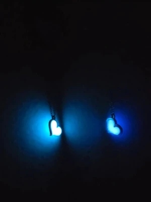 Glow in the dark hjärthalsband i rostfritt stål  - Två halsband med självlysande hjärthängen som lyser i blått i mörkret. Hängena har en stilren hjärtformad design och sitter på tunna kedjor i rostfritt stål. Perfekt för dig som vill ha något unikt och coolt smycke som verkligen syns när det är mörkt. Detaljer: Ett vitt hjärta som lyser med ett vackert turkost/blått sken i mörker. •Ett blått hjärta som lyser med ett magiskt lila sken i mörker.