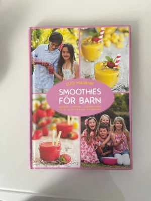 Smoothies för barn av Eliq Maranik - En färgglad och inspirerande bok med hårda pärmar, fylld med recept på smoothies för barn. Boken har ett rosa omslag med bilder på barn och fruktiga smoothies. Perfekt för dig som vill upptäcka nya smaker och lära dig mer om frukt och grönsaker.