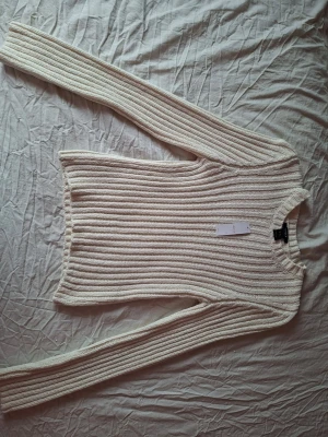 Ribbstickad beige tröja lindex - Säljer en ribbstickad beige tröja från H&M med lång ärm och rund hals. Tröjan har en klassisk, rak passform och är gjord i ett mjukt stickat material som känns skönt mot huden. Perfekt för lager på lager och enkel att matcha med olika outfits.