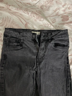 Svarta skinny jeans  - Säljer ett par svarta skinny jeans med klassisk femficksdesign och dragkedjegylf. Jeansen har bälteshällor och är i stretchigt material för en bekväm passform. De har lite större hål på knäna.