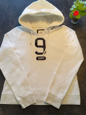 Abercrombie & Fitch Hoddie  - Fin vit abercrombie & Fitch Hoddie i väldigt bra skick. Ända dåliga är att texten är något sliten, passar XS och går bra att använda för både killar och tjejer 