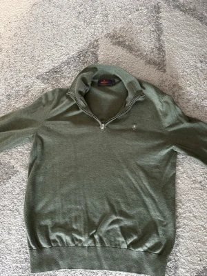Grön halvzip-tröja från Morris - Snygg grön tröja från Morris med halv dragkedja och liten broderad logga på bröstet. Tröjan har ribbade muddar vid ärmslut och nederkant samt en högre krage. Perfekt till lager-på-lager och enkel att matcha. Nypris 799kr. Pris kan diskuteras vid snabb affär. 