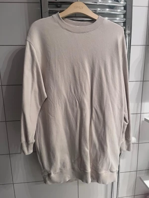 Beige sweatshirt  - En basic beige sweatshirt från Carin wester med rund halsringning och långa ärmar. Tröjan har ribbade muddar vid hals, ärmslut och nederkant. Perfekt för en avslappnad och stilren look. Tillverkad i mjukt bomullsmaterial.