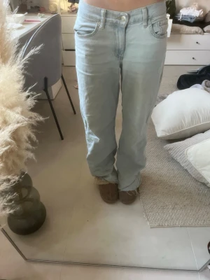 Ljusblå raka jeans - Säljer ett par ljusblå jeans med rak passform och klassisk femficksdesign. Jeansen har låg midja och är tillverkade i ett mjukt denimtyg. Perfekta för en avslappnad och trendig look.