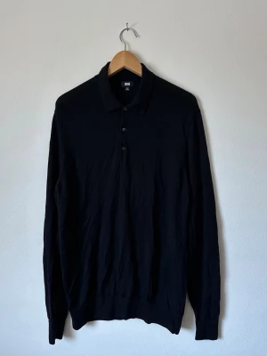 Svart långärmad pikétröja Uniqlo - Klassisk svart långärmad pikétröja från Uniqlo med krage och tre knappar framtill. Tillverkad i ett mjukt och tunt material som passar perfekt till lager på lager. Enkel och stilren design som funkar till det mesta. 8D24