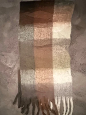 Acne studios - Acne studios halsduk med rutigt mönster i beige, brunt, grått och vitt. Tillverkad i ett mjukt material med fransar i ändarna. Perfekt för att addera lite färg till din outfit under kyliga dagar.
