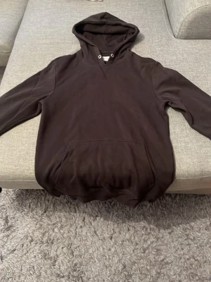 Mörkbrun hoodie med magficka PIER•ONE - En enkel och stilren mörkbrun hoodie med huva och dragsko. Hoodien har en stor magficka framtill och ribbade muddar vid ärmslut och nederkant. Perfekt för en avslappnad look och passar till det mesta. Materialet känns mjukt och bekvämt. Den passar perfekt till en 14 åring som är 165-175 cm