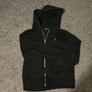 Svart hoodie från Polo Ralph Lauren - Svart hoodie från Polo Ralph Lauren med röd broderad logga på bröstet. Den är tjock och är storlek M men sitter som en S.