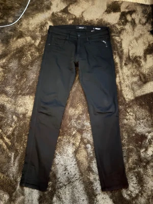 Svarta jeans från Replay - Snygga svarta jeans från Replay med klassisk femficksdesign och raka ben. Jeansen har diskreta detaljer och en stilren look som passar till det mesta. Tillverkade i ett mjukt och stretchigt material för extra komfort. Anbass fit. Priset kan diskuteras