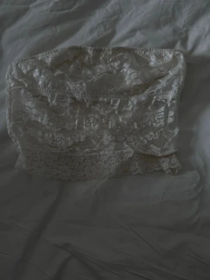 Vit spets bandeau tub topp - Säljer en vit bandeau-tub topp i mjuk spets med blommigt mönster..