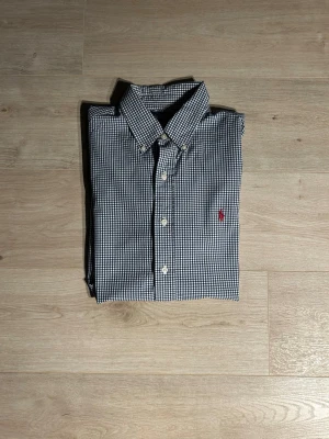 Blå Rutig Ralph Lauren Skjorta Storlek L - Klassisk Ralph Lauren skjorta i blå färg. Tröjan är i bra skick men har en fläck vid nedre delen av skjortan (SE SISTA BILD), sparsamt använd. |  Storlek: L | Skick: Bra skick! (SE SISTA BILD) | Färg: Blå| Märke: Ralph Lauren| Modell: Skjorta   |  Hör gärna av dig vid frågor så svarar jag så fort jag kan! 😁 |  