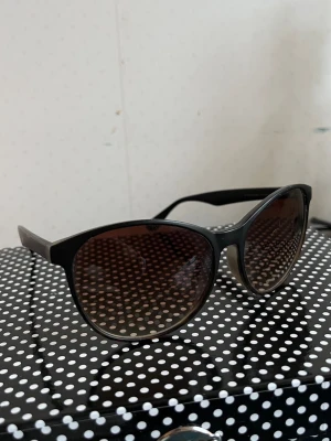 Svarta solglasögon - Snygga solglasögon med svart båge och brunt tonade glas. Smått repiga.