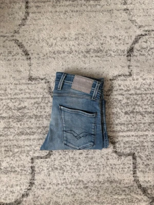 Replay anbass - Säljer ett par Replay anbass i helt okej skick, dessa har några defekter vid bakfickan och så har stål R’et gått bort Annas är de bra skick! Jeansen är i storlek 30:32 och sitter slim! Kom gärna med frågor eller funderingar samt prisförslag!