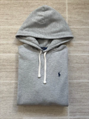 Polo Ralph Lauren Hoodie - Grå - Tjena! Säljer nu denna gråa Ralph lauren Hoodin. Skicket är 10/10, Inga fläckar, skador, inget. Säljs då den inte används så mycket. Nypris ligger på 2399, säljs nu för endast 1099. Storlek S. Pris kan diskuteras vid snabbaffär. Mvh