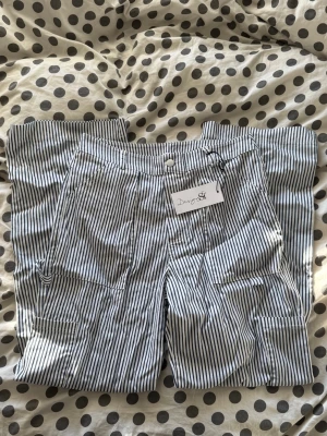 Randiga byxor - Säljer ett par oanvända byxor från Designby Si. De är randiga blå och vit. Storlek XS Petit.