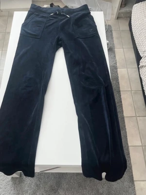 Mörkblå Juicy Couturebyxor  - Säljer ett par mörkblå mjukisbyxor från Juicy Couture. De är använda men ändå i fint skick se bild, syns endast uppe vid midjan men inget som syns utåt.