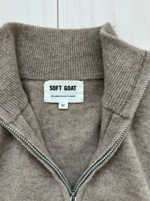 Sogt goat kvarts zip - Mjuk och stilren beige stickad tröja från Soft Goat i 100% kashmir. Tröjan har halv dragkedja, hög krage och ribbade muddar vid ärmslut och nederkant. Perfekt för dig som gillar klassisk och avslappnad stil.