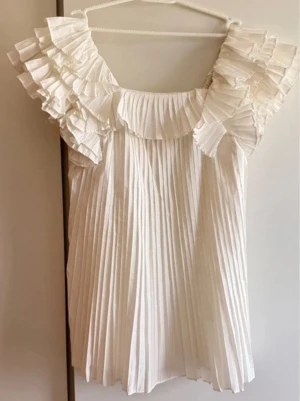 Vit plisserad klänning med volang - Supersöt vit klänning med plisserad design och stora volangdetaljer vid axlarna. Den är i mycket bra skick och storlek xs, men passar även S.💗