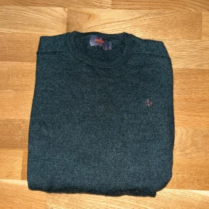 Mörkgrå stickad tröja från Morris - Snygg mörkgrå stickad tröja från Morris i 100% merinoull. Klassisk rund hals och diskret Morris-logga broderad på bröstet. Perfekt för dig som gillar stilrena och tidlösa plagg med skön passform och mjukt material. OBS LITEN I STORLEK passar snarare S/XS