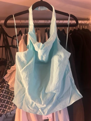 Ljusblå halterneck linnetopp - Trendig ljusblå linnetopp med halterneck och draperad framsida.