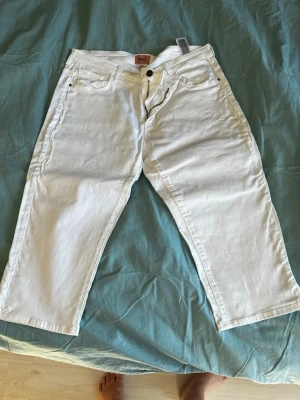 Vita raka  caprijeans från Only - Säljer ett par vita jeans i caprimodell från Only med rak passform och klassisk femficksdesign. Jeansen har knappgylf och är tillverkade i ett mjukt denimtyg. Perfekta för en clean och fräsch look.