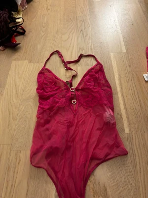 Rosa spetsbody från Intimissimi - Body från Intimissimi i transparent mesh och spets. Djup urringning med två guldfärgade ringdetaljer framtill. Justerbara axelband och v-ringad form. Aldrig använd enbart tvättad 
