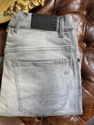 Grå slim fit jeans från Replay - Snygga grå jeans från Replay i slim fit-modell. Jeansen har klassisk femficksdesign, bälteshällor och en diskret logga på bakfickan. W31 o L32 hör av dig om några frågor 