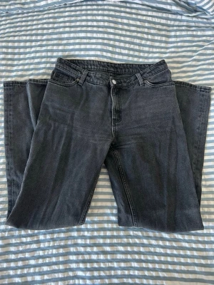 Svarta raka jeans med hög midja - Säljer ett par svarta jeans med rak passform och hög midja. Klassisk femficksmodell med knapp och dragkedja framtill. Jeansen har en snygg tvättad look och passar perfekt till en avslappnad stil. Materialet är kraftig denim i bomull. Passar till XS-S