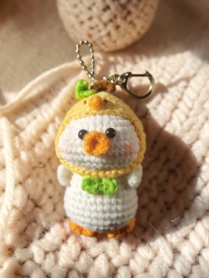 Virkad knubbig kindad anka nyckelring  - Dockan virkade med omsorg och noggrann het. Nu är den redo att få en ny ägare.  Storlek (ungefärlig)                    Huvudomkrets : 15cm                                Höjd : 8cm                                                  Bredd : 5cm (kroppen)