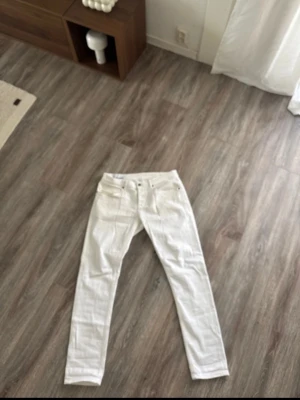 Vita dondup  - Säljer ett par vita jeans med rak passform och klassisk femficksdesign. Jeansen har bälteshällor och stängs med knapp och dragkedja. Perfekta för dig som vill ha en clean och stilren look till vardags. Materialet känns som bomull med lite stretch.