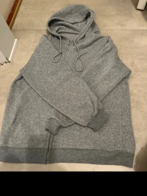 Grå hoodie med snörning - En enkel och stilren grå hoodie med huva och snörning. Hoodien har ribbade muddar vid ärmslut och nederkant samt en klassisk passform. Perfekt för chill dagar eller när du vill ha något bekvämt och snyggt. Den är från SHEIN