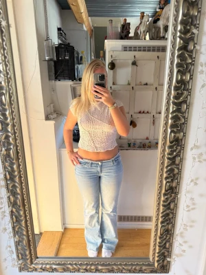 Vit virkad blus med hålmönster - Säljer en vit blus från H&M med korta ärmar och ett snyggt hålmönster över hela plagget. Materialet känns luftigt och lätt, vilket gör den superbekväm att bära.