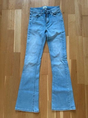 Ljusblå flared jeans från Only - Säljer ett par ljusblå flared jeans från Only. Jeansen har klassisk femficksmodell, medel-hög midja och utsvängda ben. Tillverkade i mjuk denim med dragkedja och knapp framtill. Perfekta för en trendig och avslappnad look.
