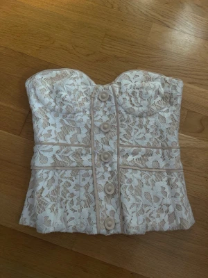  Tubtopp spets - Jätte fin tubtopp med spetsdetaljer, den har en dragkedja på baksidan och design knappar där fram. skulle tippa på att denna inte är använd