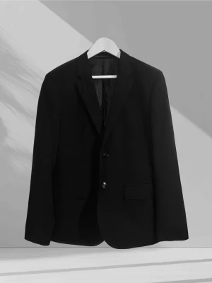 Svart kostymkavaj med klassisk passform - En svart kostymkavaj med två knappar framtill, klassisk krage och två fickor med lock. Kavajen har en tidlös design och är helfodrad för en snygg siluett. Perfekt för dig som vill ha en clean och stilren look.