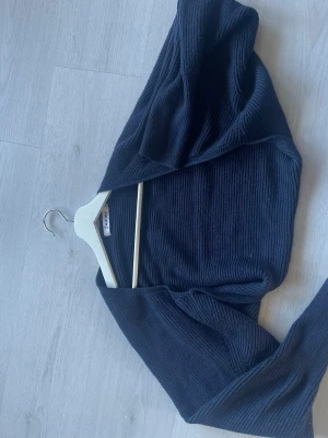 Marin blå ribbstickad bolero från Madlady! - Snygg svart ribbstickad bolero från Madlady. Modellen har långa ärmar och öppen front, perfekt att slänga över ett linne eller klänning! Materialet är mjukt och stretchigt för en bekväm passform, strl M/L