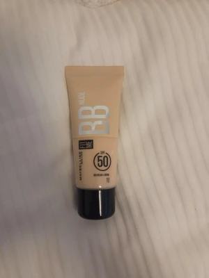 Maybelline Fit Me BB Cream Nude SPF 50 - BB-cream från Maybelline i nyansen Nude, Fit Me-serien. Tuben är beige med svart lock och har SPF 50. Ger lätt täckning och naturlig finish. Perfekt för dig som vill ha en smidig basprodukt med solskydd. Aldrig använd.