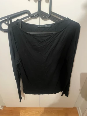 Svart långärmad topp från 157 - En enkel svart långärmad topp från 157 med rund halsringning. Tillverkad i mjukt material som känns skönt mot huden. Perfekt att matcha med jeans eller kjol för en clean look.