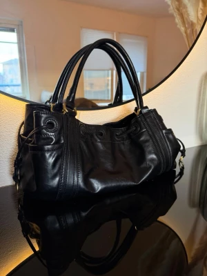 Handväska - Zara - Svart handväska med guldiga detaljer från Zara. Två innerfack med dragkedja. Använd men i fint skick! 