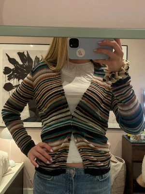 Randig kofta från Missoni - Säljer en ribbad kofta från Missoni med färgglada ränder i svart, turkos, vinrött, beige, vitt och gult. Koftan har små hål, ( se bild )