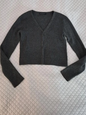 Grå cardigan Brandy Melville  - Grå ribbstickad cardigan från Brandy Melville💘 Utmärkt skick, inga anmärkningar! Säljer då jag har för många liknande.   Gör gärna en bundle för rabatt! 