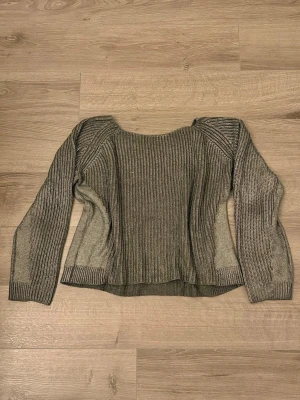 Grå metallic tröja från Gina Tricot - Säljer en silvrig stickad tröja från Gina Tricot med bred ribbstickning och rund halsringning. Tröjan har långa ärmar och en något lös passform. Skimrar fint i silver.